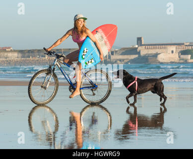 Woman riding sur son vélo avec son chien le long de la plage. Tarifa, Costa de la Luz, Cadix, Andalousie, Espagne du Sud. Banque D'Images