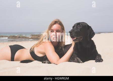 Adolescent blond avec son animal de Labrador à la plage. Banque D'Images