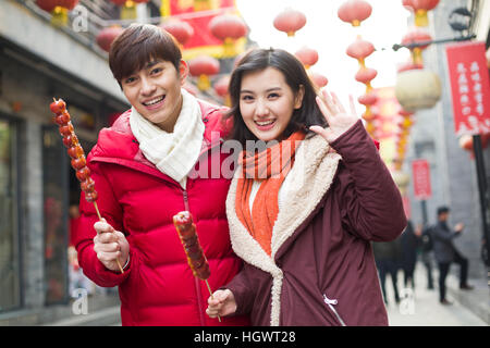 Jeune couple avec fruits confits haw célébrant le Nouvel An chinois Banque D'Images