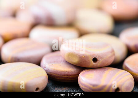 Collection de pièces de monnaie hickoryite multicolores en forme de perles sur plaque en fonte noire. Hickoryite est une variété de rhyolite. Banque D'Images