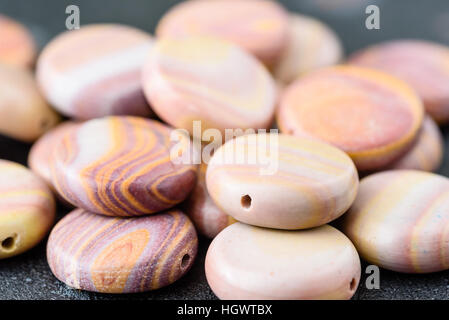 Collection de pièces de monnaie hickoryite multicolores en forme de perles sur plaque en fonte noire. Hickoryite est une variété de rhyolite. Banque D'Images