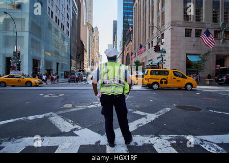 Policier du NYPD debout sur un passage piétons sur la 5e avenue, avec les taxis jaunes à la 57e rue vers le bas Banque D'Images