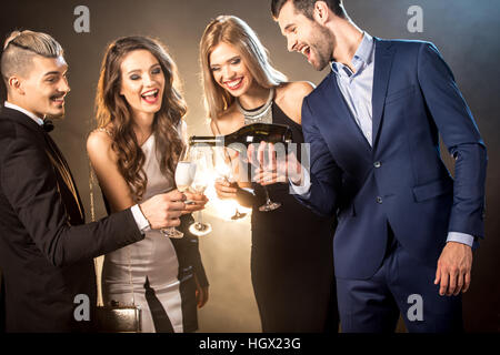 Heureux jeune élégant friends drinking champagne tout en célébrant Banque D'Images
