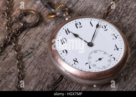 Ancienne montre de poche sur une chaîne sur une vieille table de bois macro Banque D'Images