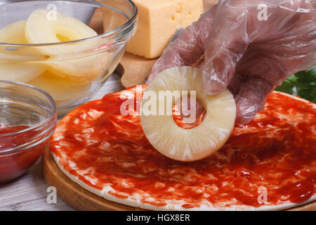 Le chef met la main anneaux d'ananas sur les pizzas close up horizontale. Banque D'Images