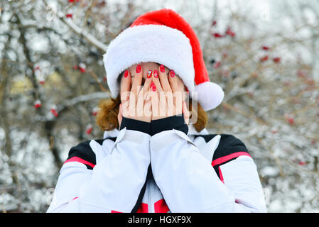 Femme au cap Santa Claus couvre son visage avec ses mains Banque D'Images