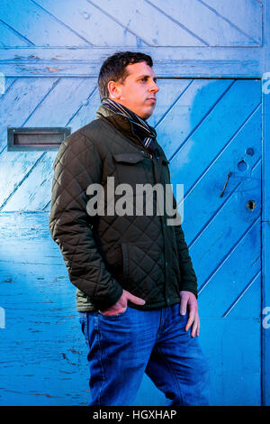 L'homme de profil devant une porte en bois bleu Banque D'Images
