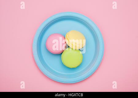 Trois macarons rose, vert et jaune sur plaque bleue Banque D'Images