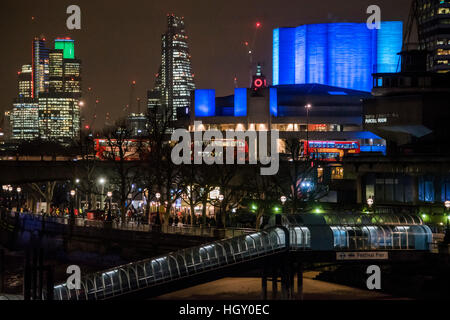 Le Théâtre National s'illumine en bleu en raison d'sponsoship Travelex. Il se reflète dans la rivière Thameswith la ville et l'Oxo tower en arrière-plan. Banque D'Images