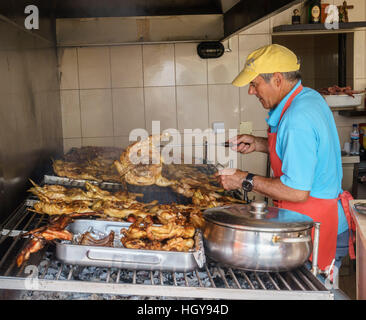 Man cooking poulets sur un grill traditionnel Banque D'Images