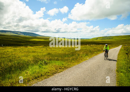 Cycliste féminine sur route vide sur l'île d'Islay Ecosse Banque D'Images