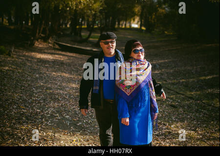 Hot couple walking in autumn park. mari et femme la marche à l'extérieur à l'automne derniers jours, l'homme avec une moustache portant des lunettes de soleil Banque D'Images