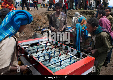 Place du marché. Déchargent. Les montagnes du Simien. Le nord de l'Éthiopie. Marché écorcer. Plusieurs enfants jouer au baby-foot pendant que leurs parents vendent ou achètent. E Banque D'Images