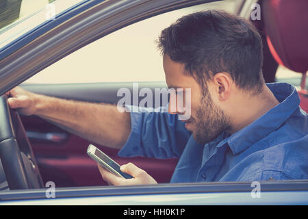 Portrait de beau jeune homme d'affaires à l'aide de SMS sur téléphone mobile en conduisant une voiture Banque D'Images