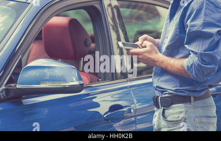 Téléphone Mobile apps pour les propriétaires de voiture concept. L'homme à l'aide de smart phone pour vérifier l'état, contrôler sa nouvelle voiture Banque D'Images