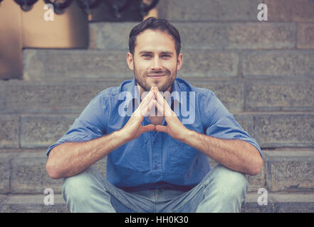 Closeup portrait of happy young man smiling sitting moderne en plein air Banque D'Images