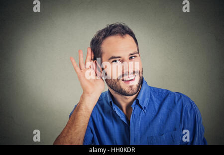 Beau jeune homme d'affaires de Nosy Be dans l'écoute en secret sur la conversation, part à l'oreille, souriant à potins juteux avec sourire sur le visage Banque D'Images