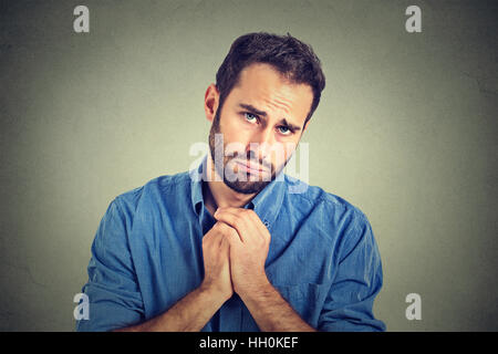 Homme désespéré montrant les mains jointes jolie veuillez avec du sucre sur le dessus isolé sur fond gris. L'expression faciale des émotions humaines Banque D'Images