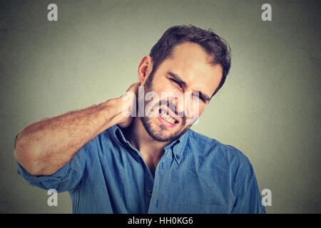 A souligné, jeune homme à la mauvaise douleur du cou, après de longues heures de travail étudiant isolé sur fond gris. L'émotion négative Banque D'Images