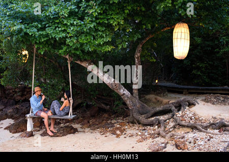 Un couple dans un swing romantique dans la plage de Six Senses Resort, Koh Yao Noi, Phang Nga Bay, en Thaïlande, en Asie. Six Senses Yao Noi donne le plus haut benchm Banque D'Images