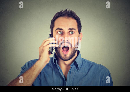 Choqué man talking on mobile phone Banque D'Images