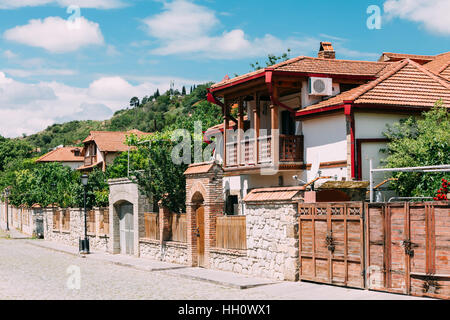 Mtskheta (Géorgie). Le Livre Blanc Belle maison de campagne avec toit en tuiles rouges et balcon en bois dans l'agréable rue pavée de bleu sous l'été Banque D'Images