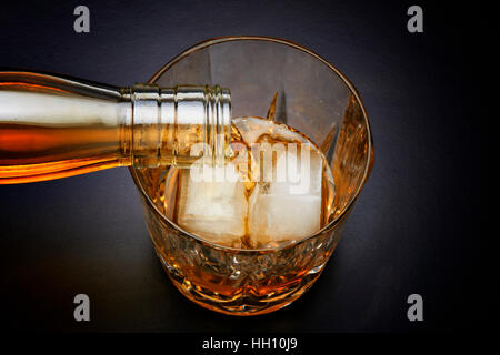 Verser dans le verre de whisky avec deux cube de glace Banque D'Images