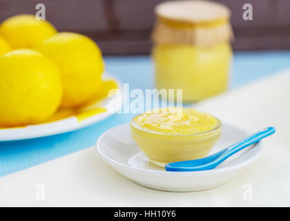 Produits frais bio lait caillé de citron maison montrant les citrons et le lait caillé de citron dans un bocal et plat en verre, joli en bleu clair et jaune, prix pour copy space Banque D'Images