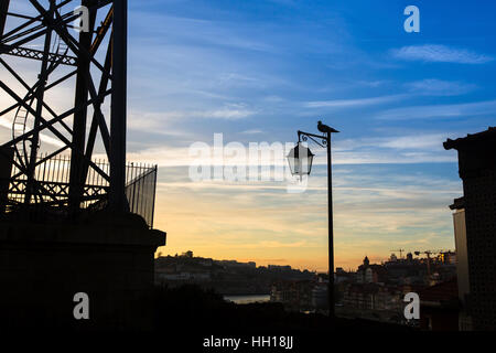 Silhouette de lampe avec oiseau sur fond de la ville et le ciel bleu. Banque D'Images