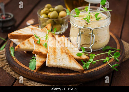 Poulet Pate - rillette, toasts, olives et d'herbes sur une planche en bois Banque D'Images