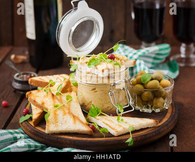 Poulet Pate - rillette, toasts, olives et d'herbes sur une planche en bois Banque D'Images