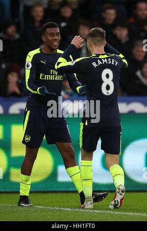 L'arsenal Alex Iwobi (à gauche) célèbre son deuxième but de côtés du jeu après son tir a été dévié résultant en un objectif propre pour Swansea City's Jack Cork (pas sur la photo) au cours de la Premier League match au Liberty Stadium, Swansea. Banque D'Images