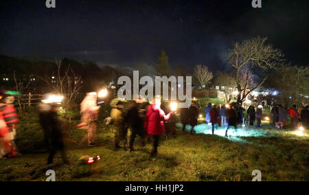 Les villageois et les rangers du National Trust à pied à travers le village verger car ils prennent part à une wassail sur le National Trust Madehurst Estate, Sussex de l'Ouest. Banque D'Images