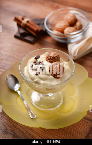 Dessert vanille dans la tasse en verre décoré avec du chocolat râpé et biscuits amaretti Banque D'Images