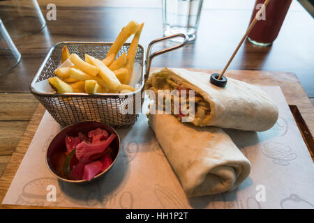 Wrap Shawarma de poulet servi sur une planche en bois avec frites et salade Banque D'Images