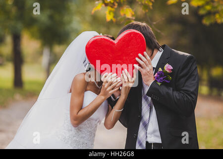 Happy wedding couple détient big red heart en mains. Le marié et la mariée tenir dans la main. Banque D'Images