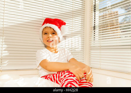 Garçon en costume du Père Noël assis sur son lit de rêve Banque D'Images