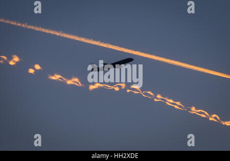 Un avion du passager (haut) croise deux traînées de condensation la foudre en rouge pendant le coucher du soleil à Francfort/Main, Allemagne, le 6 janvier 2017. Photo : Frank Rumpenhorst/dpa Banque D'Images