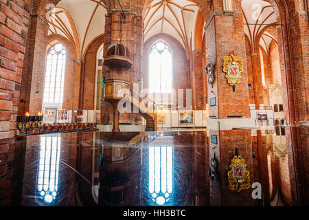 Riga, Lettonie - 1 juillet 2016 : Chaire en bois avec des escaliers dans l'intérieur de l'église Saint Pierre, éclairée par la lumière du soleil à travers l'arche Fenêtre, reflétée sur bl Banque D'Images