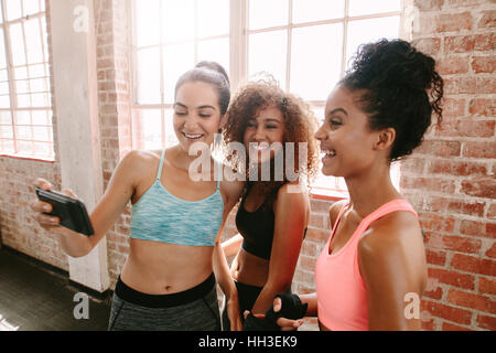 Groupe de femmes dans la catégorie remise en forme prendre pendant la pause selfies. Les amis de prendre une formation de remise en forme après selfies en salle de sport. Banque D'Images