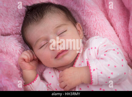 A moins de trois semaines d'âge mignon bébé, profondément dormir sur une couverture rose Nouveau-né à la couverture a augmenté de manière monotone profondément Banque D'Images