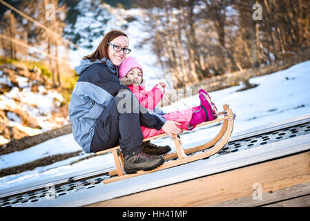 La mère et le petit enfant sur un convoyeur de ski sur un traîneau dans station de ski de l'école de ski. Banque D'Images