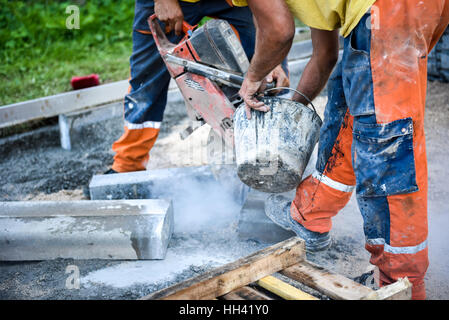 Travailleur de la construction des chaussées en béton ou en métal poignarde pour trottoir à l'aide d'un cut-off a vu. Sur le profil de la lame de coupe d'asphalte ou de béton wit Banque D'Images