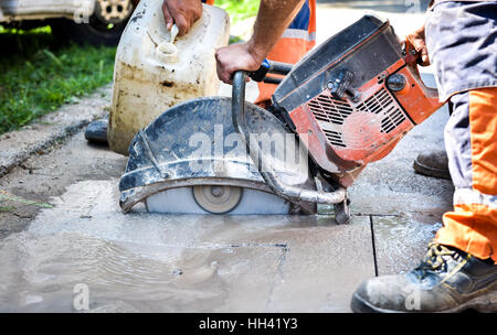 Travailleur de la construction d'asphalte pour pavage de coupe à l'aide d'un trottoir pour poignarde cut-off a vu. Sur le profil de la lame de coupe d'asphalte ou de béton avec les travailleurs Banque D'Images