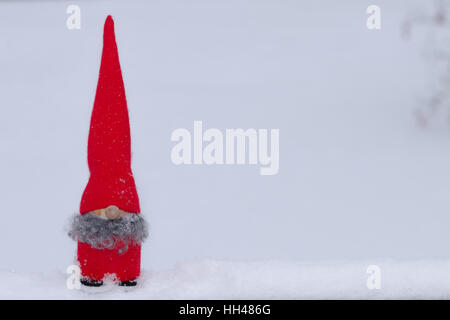 Un gnome ludique se trouve dans la vraie neige avec de l'espace pour copier ou texte Banque D'Images