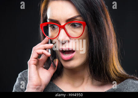 Close-up portrait of woman in red lunettes talking on mobile phone Banque D'Images