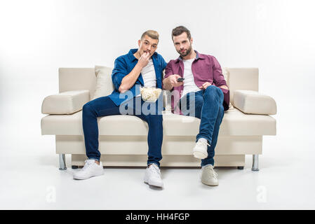 Amis des hommes assis sur table avec pop-corn et regarder la télévision Banque D'Images