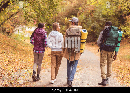 Vue arrière de jeunes backpackers marche sur route en forêt d'automne Banque D'Images