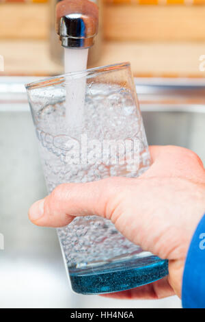 Capture d'un point de vue d'un homme de servir un verre d'eau douce dans un robinet de cuisine Banque D'Images