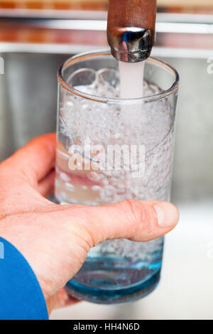 Libre tourné d'un homme de servir un verre d'eau douce dans un robinet de cuisine Banque D'Images